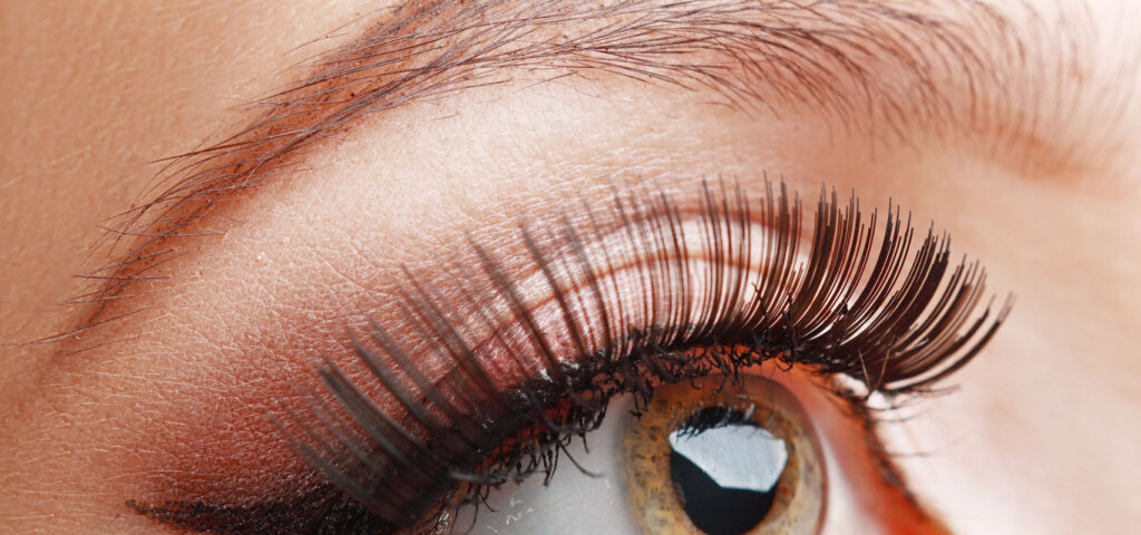 Zbliżenie na oko z długimi rzęsami i zadbanymi brwiami – kosmetyka i pielęgnacja Zbliżenie na oko osoby z długimi rzęsami i zadbanymi brwiami, ilustrujące efekty odpowiedniej pielęgnacji i kosmetyki rzęs oraz brwi
